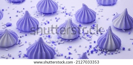 Very Peri pastel colored meringues with  sweet candy on purple lilac pastel background. Color of the year 2022. Happy birthday greeting card. Sweet candy concept. Banner.                           
