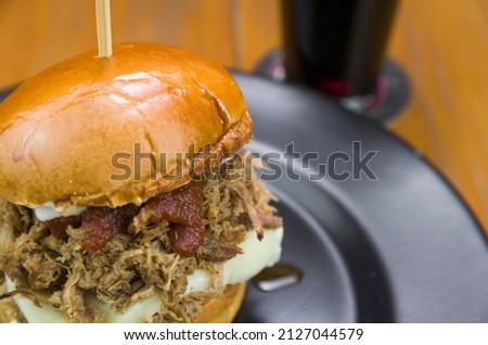 Close-up of tasty homemade pulled pork burger on wooden table and black background