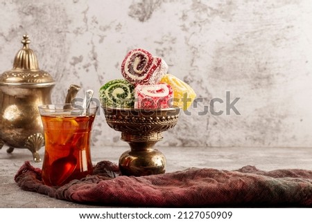 Traditional Turkish delight with Turkish tea on gray background. Ramadan Kareem celebration concept. Fragrant Turkish tea and Turkish sweets in national dishes. Royalty-Free Stock Photo #2127050909