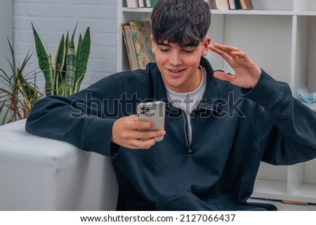 young man with mobile phone at home talking by video conference or streaming