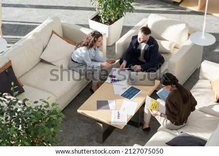 Young female manager of high tech corporation making report about web analytics and statistics to ceo by workplace at meeting