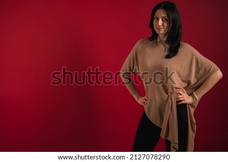 Portrait of a pretty, emotional, beautiful interesting cheerful brunette who thinks too much, looks straight, isolated on a bright red background.