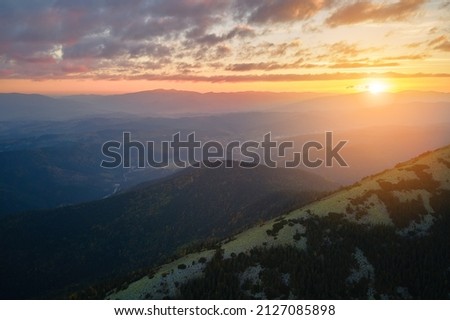 Aerial view of bright foggy morning over dark peak with mountain forest trees at autumn sunrise. Beautiful scenery of wild woodland at dawn Royalty-Free Stock Photo #2127085898