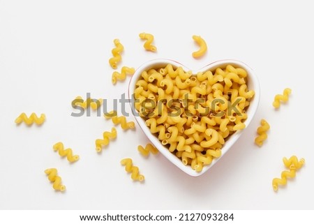 Raw pasta cavatappi in heart bowl. Top view of Italian cuisine ingredient. Royalty-Free Stock Photo #2127093284