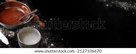 Pastry tools with chocolate residues icing sugar and flour on black background in banner format