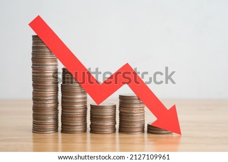 Stack of coins bar chart and red graph trending downwards with white wall background on wooden table copy space. Economy recession crisis, inflation, stagflation, business and financial loss concept.