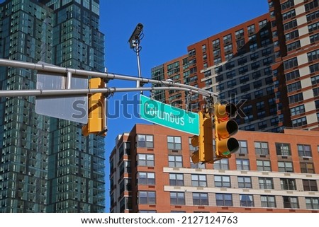 Green big Columbus Drive sign hanging on a arch pole between traffic lights in the streets of downtown Jersey City