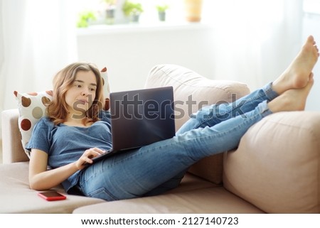 Woman working with laptop computer lying on sofa at home. Freelancer or blogger. Distance learning. Additional education. Retraining courses. Business online for adults. Social media addiction Royalty-Free Stock Photo #2127140723