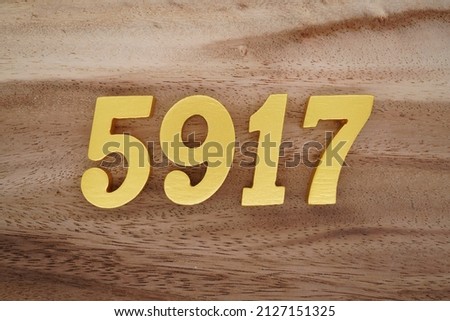 Wooden  numerals 5917 painted in gold on a dark brown and white patterned plank background.