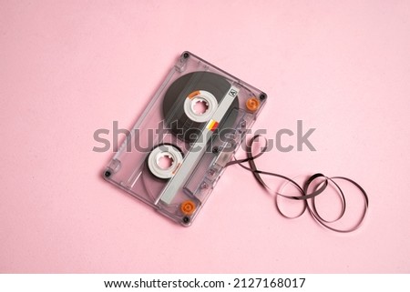 Audio cassette tape on pink background, tape pulled of , top view 