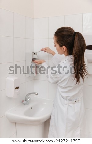 The doctor in white uniform disinfects his hands. Surgeon washing hands hospital concept. The nurse washes her hands with sanitizer or dispenser or alcohol solution for hand disinfection, close-up.