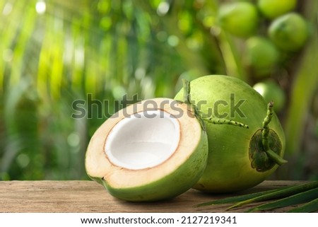 Coconut juice in half fruit with coconut tree background. Royalty-Free Stock Photo #2127219341