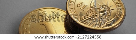 Ukrainian coin of 1 hryvnia and US coin of one dollar close-up. Hang over a gray paper surface. Banner or headline about money economy and central bank of Ukraine. Macro