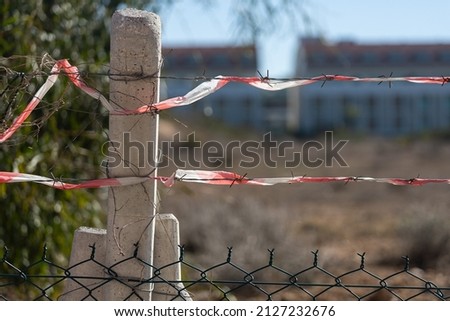 Close-up of a rusty thorn, wire, custodial barbed wire, against the background of plants, soft focus