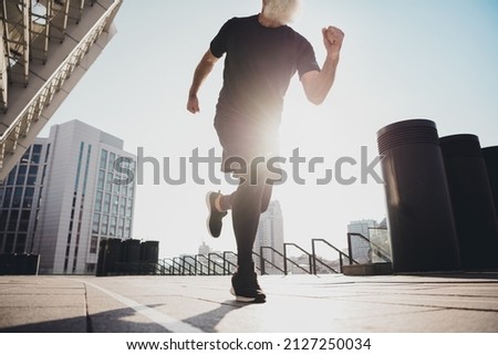 Photo of pretty sportive man pensioner dressed black clothes running fast everyday morning routine outdoors city street