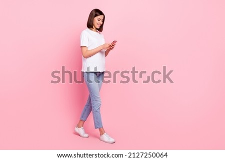 Full length body size view of attractive cheerful girl going using device browsing web isolated over pink pastel color background Royalty-Free Stock Photo #2127250064