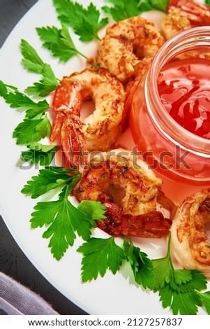Grilled shrimps on white plate with fresh parsley, spices and lemon, fried prawns with sauce in jar
