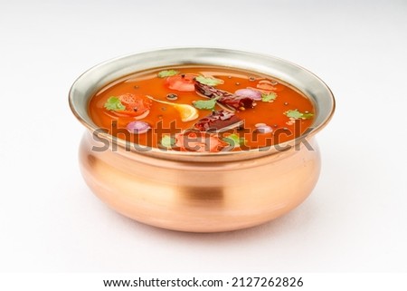Rasam, south indians main item in meal, a veg soup which is very spicy-sweet-sour stock and healthy food item  which is traditionally arranged in a brass vessel with white background