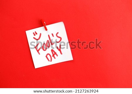 sticker with text fools day hanging on the pin on red background. Copy space for text