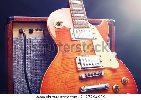 Combo amplifier for electric guitar with honey sunburst guitar on the black background. Gently toned.