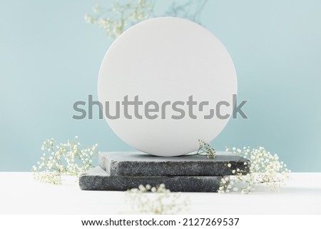 Podium for cosmetic product presentation. Abstract minimal geometrical form. Cylinder podium with white flowers, geometric shadows. Scene to show products. Showcase, display case.