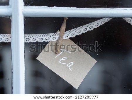 Tea sign pegged to lace in shop window advertising hot drinks to customers of takeaway café. 