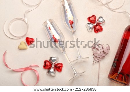 Different chocolate candies in shape of heart and glasses on light background. Valentine's Day celebration