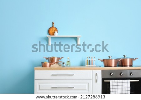 Modern kitchen with cooking pots and shelf near color wall Royalty-Free Stock Photo #2127286913