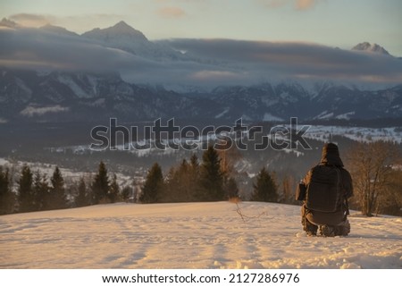 Photographer taking pictures of mountain landscape in winter