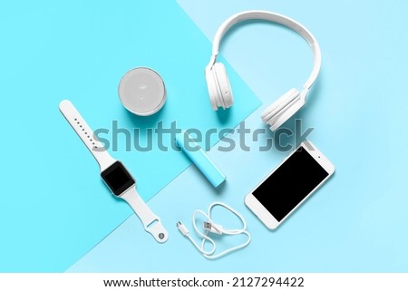 Modern gadgets with power bank on blue background Royalty-Free Stock Photo #2127294422