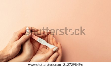 Pregnancy test positive. Female hand hold positive pregnant test with silk ribbon on pink background. Medical healthcare gynecological, pregnancy fertility maternity people concept