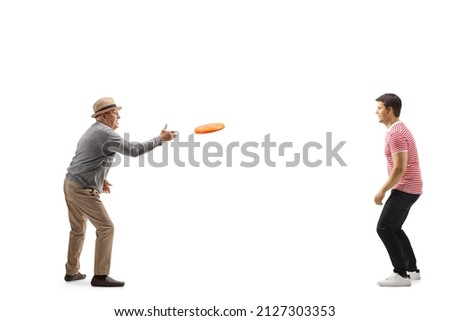 Full length shot of an elderly man throwing a plastic disk with a younger man isolated on white background