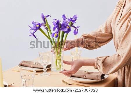 Minimal close up of young woman decorating dinner table with elegant Iris flowers for Spring, copy space Royalty-Free Stock Photo #2127307928