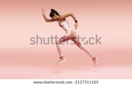 Sporty young woman running. Full length profile photo of lady jump high up training marathon finish line wear sports suit shoes isolated pink color background