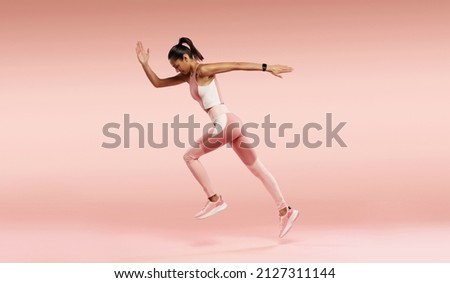 Sporty young woman running. Full length profile photo of lady jump high up training marathon finish line wear sports suit shoes isolated pink color background