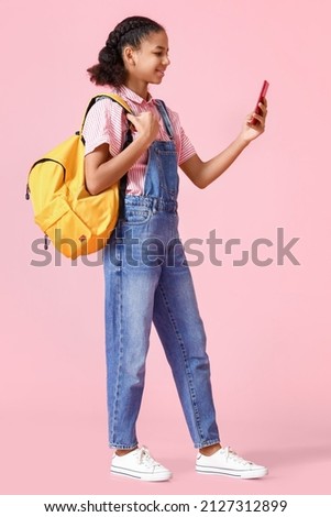 African-American female student with phone on pink background