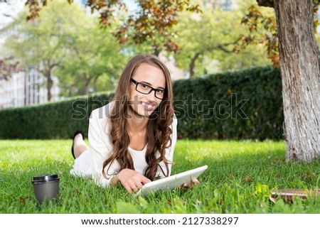 Happy young woman with digital tablet laying on grass