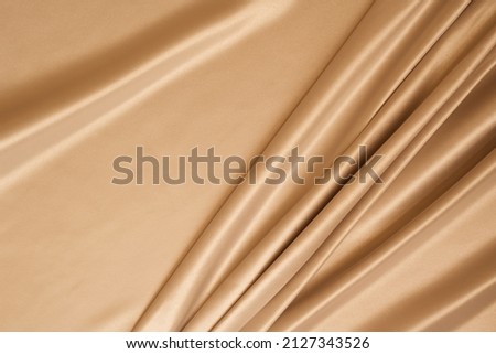 Beautiful elegant wavy beige or light brown satin silk luxury cloth fabric texture, abstract background design. Copy space. Card or banner