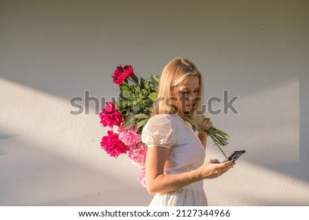 Outdoor portrait of young redhead woman in vintage wedding dress with big bouquet of pink peonies. Womans Day. Female spring, summer fashion concept. Wedding day. The flowers delivery.