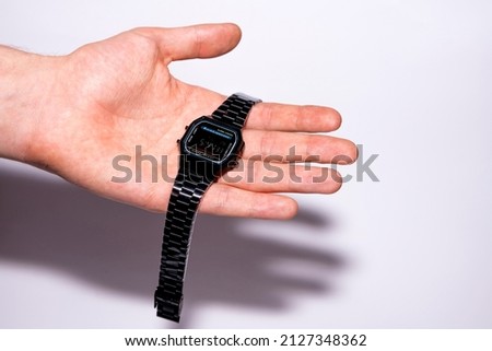 Black electronic watch in a metal case on a human palm. Brand new watch with protective film. Clock isolated on white background. Royalty-Free Stock Photo #2127348362