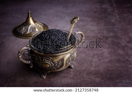 Salted black caviar in a metal dish on a dark stone background. Selective focus.