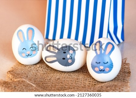 Easter eggs with a bunny pattern next to a gift bag. easter bunny painted on a white egg