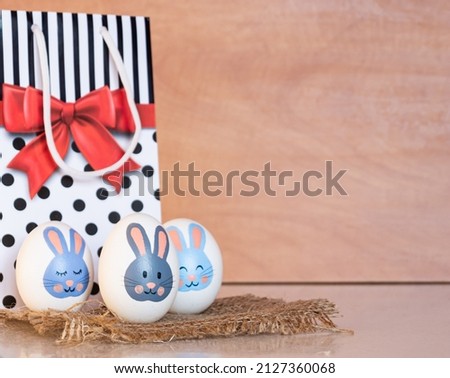 Easter eggs with a bunny pattern next to a gift bag. easter bunny painted on a white egg