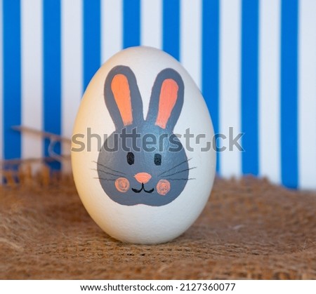 Easter egg with a bunny pattern next to a gift bag. easter bunny painted on a white egg