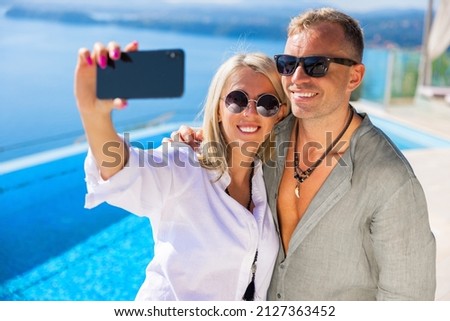 Couple making selfie picture by the hotel pool while on vacation