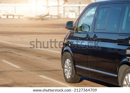 Side back view of black VIP service van running on airport taxiway with terminal building on background. Business class taxi service at airport. Security intelligence agency hurrying at airfield Royalty-Free Stock Photo #2127364709