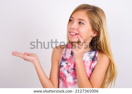 Positive little caucasian kid girl wearing sport clothing over white background advert promo touch finger teeth