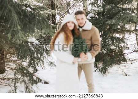 blurred photo young couple in love man and woman in fashion stylish winter clothes in snowy pine forest and having fun spending time together, concept of valentine's day and newlyweds, tenderness