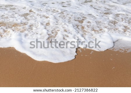 Beautiful waves foam and roll onto the shore. Marine picture, sea  sandy beach. Foam on the sand.
Desktop design. Wallpaper design for website