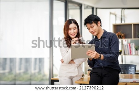 Entrepreneur Asian businessman and businesswoman discussing new business project in tablet in modern Meeting In Modern Office, Asian business casual concept. Royalty-Free Stock Photo #2127390212